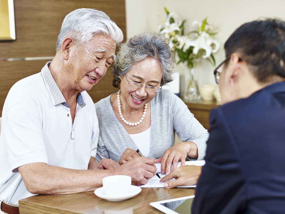 Senior Asian man and woman signing a document.